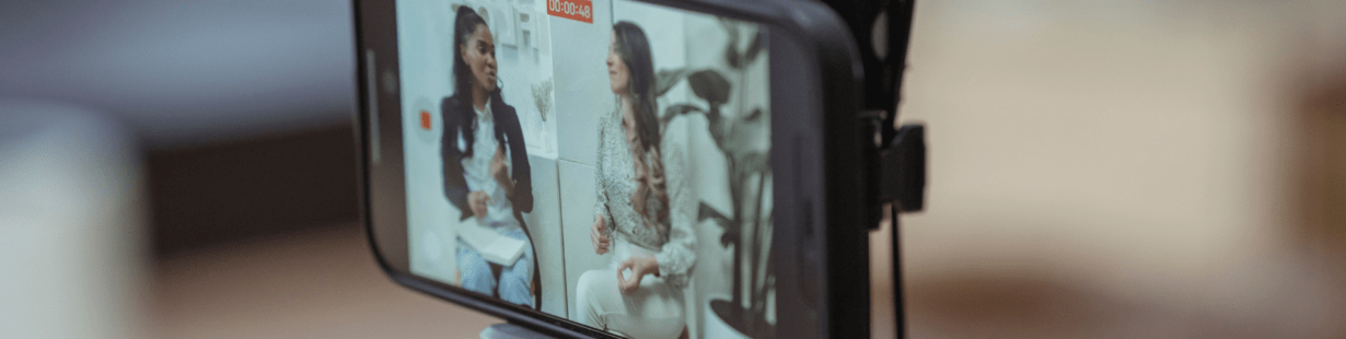 Téléphone posé sur un trépied filmant deux femmes qui discutent en mode paysage